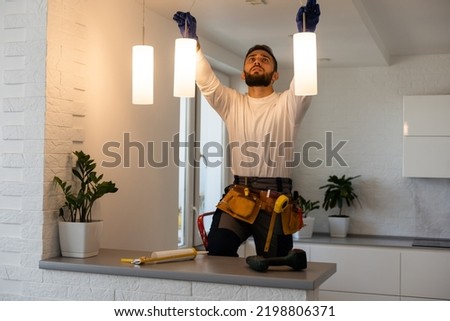 Electrician worker installation electric lamps light inside apartment. Construction decoration concept. Royalty-Free Stock Photo #2198806371