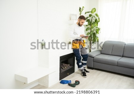 Professional technician with screwdriver installing electric fireplace in room
