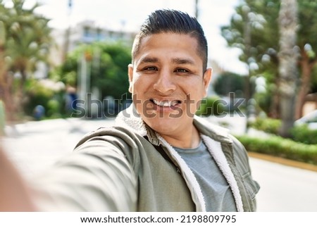 Young latin man smiling happy make selfie by the camera at the city.