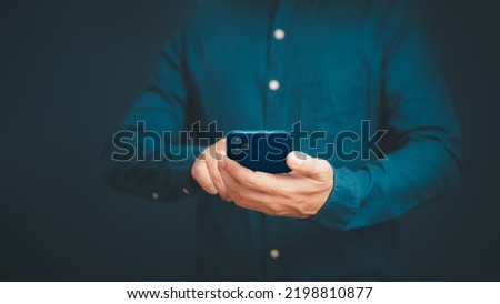 Closeup image of a man holding and using mobile phone or smartphone in room.