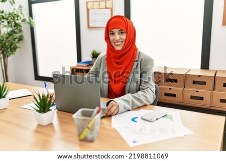 Young woman wearing arabic scarf using laptop working at office