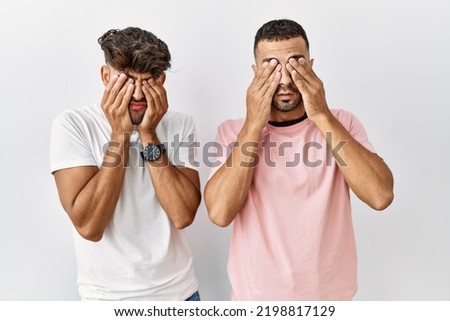 Young gay couple standing over isolated background rubbing eyes for fatigue and headache, sleepy and tired expression. vision problem 