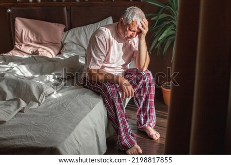 Sad senior man in pajamas suffering from headache sitting on bed at home bedroom, health, old age and people concept Royalty-Free Stock Photo #2198817855