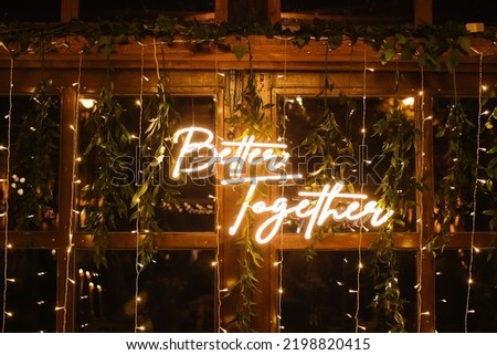 Wedding day neon text. Wedding venue decoration. Boho style leaves decorations. Rustic wedding party in wooden barn with glass windows. Closeup better together banner.