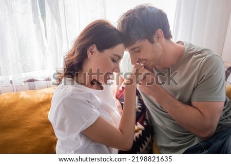 Young man kissing hand of brunette girlfriend on bed in camper van Royalty-Free Stock Photo #2198821635