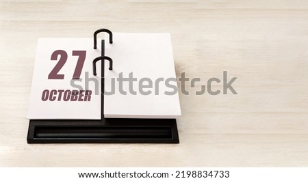 october 27. 27th day of month, calendar date. Stand for desktop calendar on beige wooden background. Concept of day of year, time planner, autumn month.