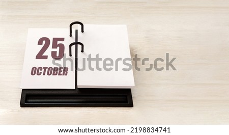 october 25. 25th day of month, calendar date. Stand for desktop calendar on beige wooden background. Concept of day of year, time planner, autumn month.