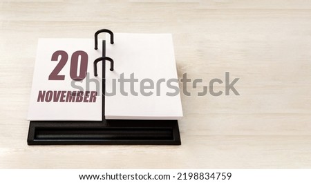 november 20. 20th day of month, calendar date. Stand for desktop calendar on beige wooden background. Concept of day of year, time planner, autumn month.