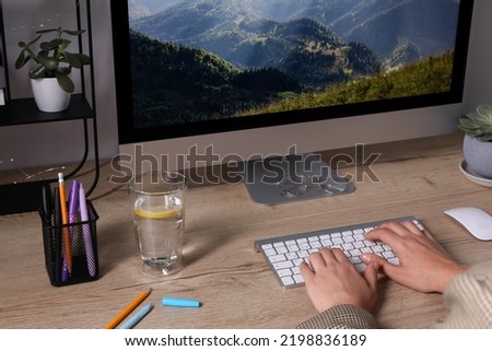 Woman working on computer at wooden table in room, closeup