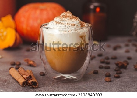 A glass of autumn pumpkin latte with whipped cream and spices. Coffee with pumpkin and cinnamon on a dark background