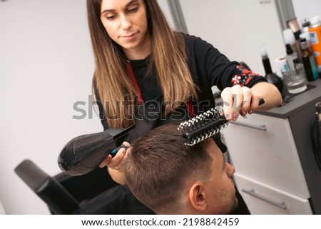 Hair salon master blow dry hair client at barber shop. Male client getting haircut by hairdresser. Hair care, beauty industry, barber concept.