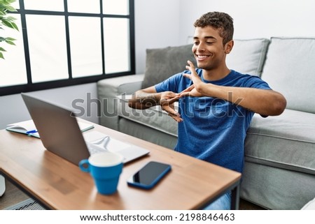 Young hispanic man gesturing sign language on video call at home Royalty-Free Stock Photo #2198846463