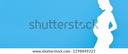 Concept of pregnancy. Paper silhouette of a pregnant woman on a blue background. Flat lay, place for text. Banner with place for text.