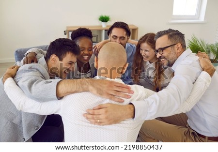 Team of successful positive colleagues laughing and hugging while standing in circle in office. Cheerful business colleagues celebrate their success together. Concept of cohesion and teamwork. Royalty-Free Stock Photo #2198850437