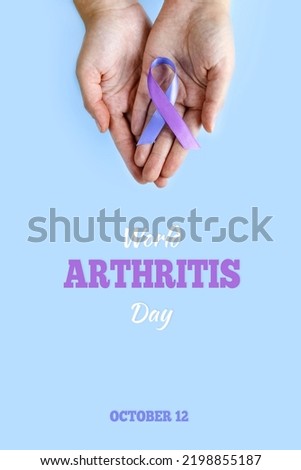 World Arthritis Day. October 12. Adult hands holding blue purple ribbon on blue background. Rheumatoid arthritis illness disease. vertically photo