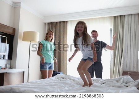 Happy family mother father and child laughing play and jump in bed in bedroom at home or hotel