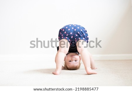 Happy cute caucasian one year old child standing upside down Royalty-Free Stock Photo #2198885477