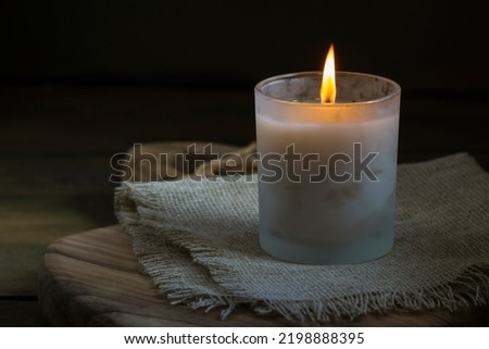 Burning white candle light on old dark wooden table background  burlap sack Halloween Aromatherapy smoke rustic cutting board napkin christmas blue cozy textile