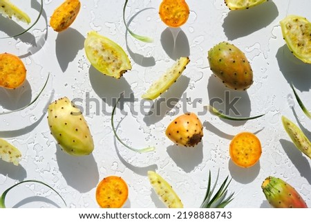 Exotic fruits, yellow and orange prickly pears, healthy cactus fruits on off white background with leaf. Flat lay, direct sunlight with shadows. Wet background with traces of water. Royalty-Free Stock Photo #2198888743