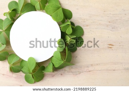 Frame of clover leaves and blank card on light table, flat lay with space for text. St. Patrick's Day celebration
