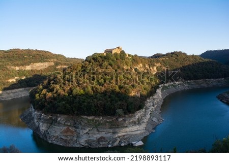 Monastery or old house on the top of mountain and green trees with a blue river below in the shape of a u-shape traveling on vacation and discovering unique places where you can take a good picture  