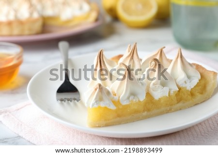 Piece of delicious lemon meringue pie served on white marble table, closeup