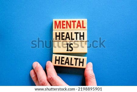 Mental health psychological symbol. Concept words Mental health is health on wooden blocks on a beautiful blue table blue background. Psychologist hand. Psychological mental health concept.