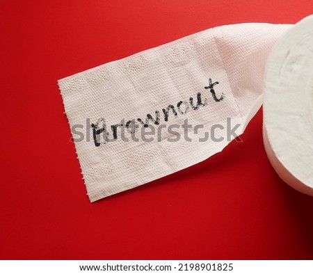 Toilet paper on red background with handwritten word BROWNOUT - Employees feel overworked, demotivated and disengaged – which is essentially the stage before burnout