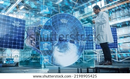 Male Engineer Uses Tablet Computer for Satellite Construction. Aerospace Agency: Scientist uses Digitalization and Visualization in Augmented Reality for Building Exploration Spacecraft Royalty-Free Stock Photo #2198905425