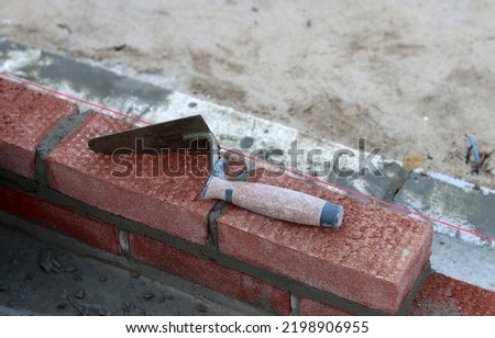 Brick trowel on a wall. Close up photo of builder tool. Construction site. 