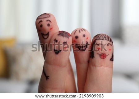 Four fingers with drawings of happy faces on blurred background