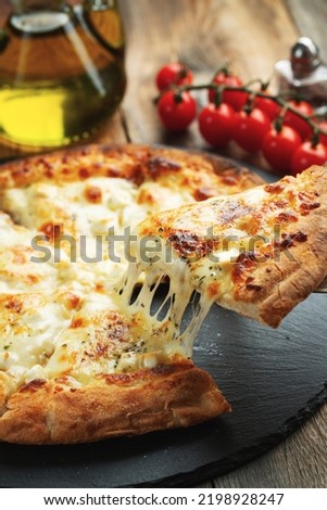 A slice of hot Italian pizza with stretching cheese. Pizza four cheeses with basil. Royalty-Free Stock Photo #2198928247
