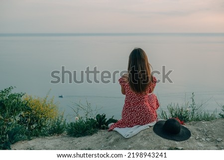 young woman sitting on a mountain in summer, view from the back