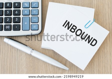 INBOUND text on a card on a paper clip to the notes on a wooden table