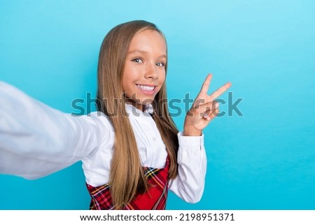 Selfie photo of young pretty nice smile girl school uniform showing v-sign hello world popular blog isolated on blue color background