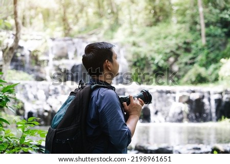 Professional photographers capture the beauty of nature with photographic equipment at a tropical waterfall.Concept of Photography and Travel