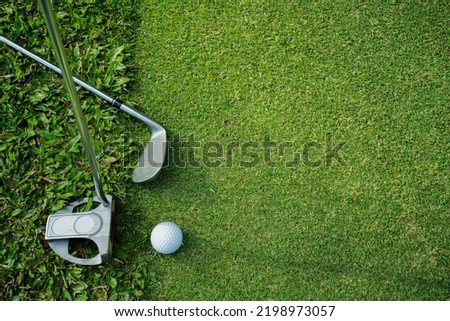 Golf clubs and golf balls on a green lawn in a beautiful golf course with morning sunshine. 