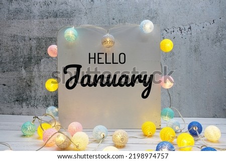 Hello January text message with LED cotton ball decoration on wooden background