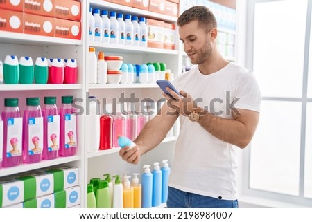Young caucasian man customer make photo by smartphone to deodorant at pharmacy