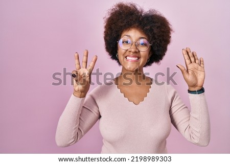 Young african american woman standing over pink background showing and pointing up with fingers number eight while smiling confident and happy. 