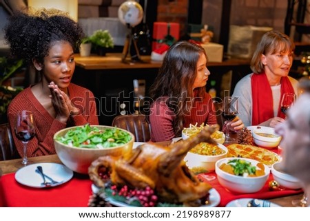 At home family decoration gift box in background on festive christmas tree and cheerful serving roasted turkey and cheers drink red wine talking to each other while dinner
