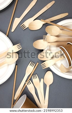 Set of disposable wooden tableware on a gray background. Flat lay.