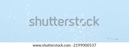 Sparkling silver glitter on blue background banner texture. Abstract holiday blurred lights header. Wide screen wallpaper. Panoramic web banner with copy space for design