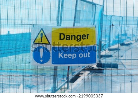 yellow and blue danger keep out sign against blue mesh construction background