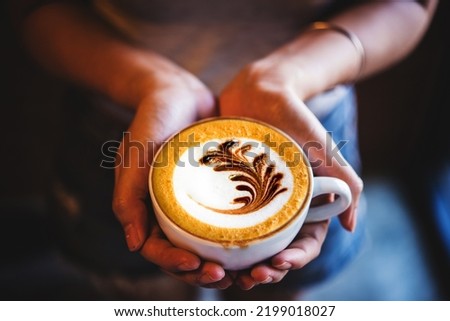 Top view of a Late art coffee cup on woman hand in the morning, classic retro warm tone	
