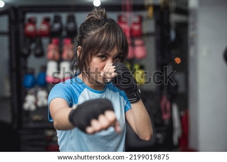 A young mixed martial arts athlete fiercely poses for the camera while demonstrating the proper fighting stance in throwing a punch. Royalty-Free Stock Photo #2199019875
