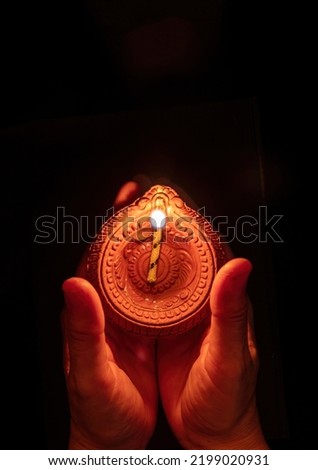 Diwali, Deepavali Hindu Festival of lights celebration. Diya oil lamp lit in woman hands, dark background. top view. 
 Royalty-Free Stock Photo #2199020931