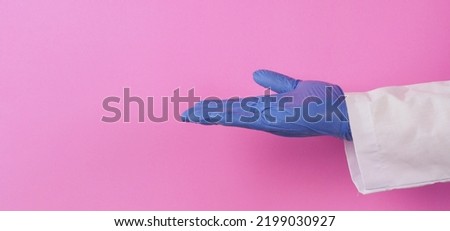 Empty Hand wear doctor gown and violet medical glove on pink background. Studio shooting.