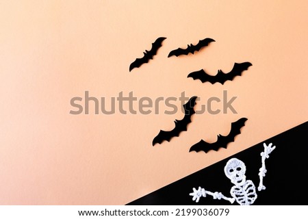 Composition of black bats on an orange background and a knitted white skeleton on a black background. Halloween concept.