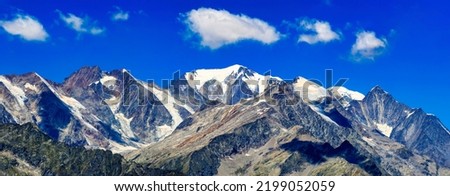 Panorama of snow capped mountain peaks. Snowy mountain peak panorama. Snowy mountain peaks panoramic landscape. Beautiful mountain panorama Royalty-Free Stock Photo #2199052059